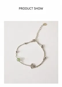 Close-up of S925 silver butterfly bracelet with green jade bead on a warm beige background