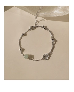 Detail of silver chain bracelet with a green jade bead and delicate butterfly charm
