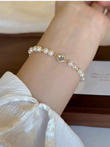 Detailed shot of pearl bracelet with gold clover pendant on a female wrist