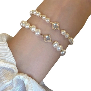 Elegant pearl bracelet set with golden clover charm worn on female wrist for a stylish look