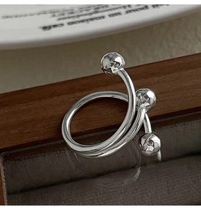 Close-up of a silver triple-layered wrap ring with hammered beads on dark wood