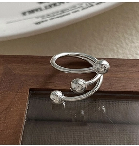 Macro shot of silver spiral ring with textured beads on a ceramic plate background