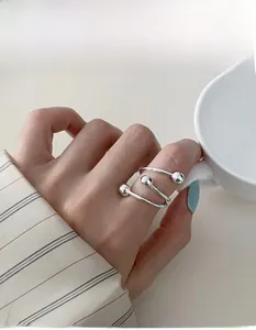 Detail of silver spiral bead ring on finger holding a minimalist white ceramic cup