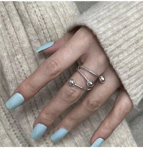Detail of silver spiral wrap ring with three bead accents on a model with blue nails