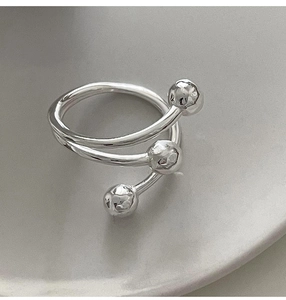 Macro shot of silver multilayer spiral ring with three beads on a ceramic tray