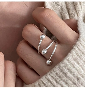 Close-up of minimalist triple layer spiral silver ring with geometric beads on finger