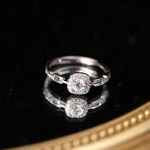 Elegant square cushion cut halo ring with side stone accents on a black reflective surface