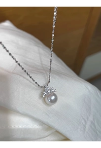 Gros plan détaillé du pendentif couronne en perle sur un fond de tissu satiné blanc