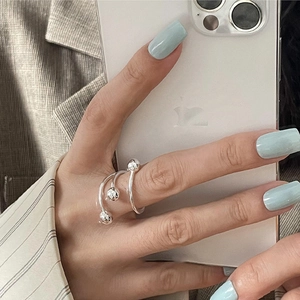Minimalist silver wrap ring with three beads shown on finger in a modern style