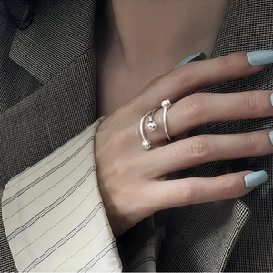 Minimalist silver triple spiral ring with beads on a hand wearing a grey suit jacket