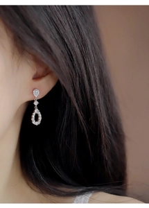 Close-up of a teardrop zircon earring showing hollow design and sparkling silver texture
