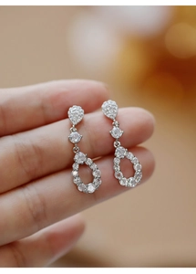Macro shot of silver teardrop earrings with pavé-set zircons and hollow design