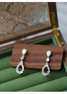 Macro shot of silver teardrop earrings with cubic zirconia on vintage wood display