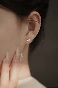 Gros plan d'un clou d'oreille feuille argentée minimaliste avec détails de veines sur un mannequin