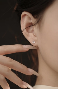 Gros plan d'une boucle d'oreille feuille d'argent portée sur une oreille féminine