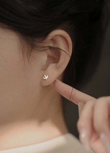 Gros plan d'un clou d'oreille feuille argentée avec fermoir à vis sur modèle féminin