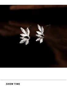 Vue macro de boucles d'oreilles feuilles en argent avec nervures sur surface miroir noire