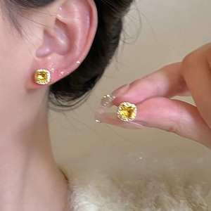 Detail of square yellow zircon stud earrings with micro diamond halo on a model ear