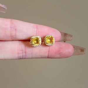 Close-up of yellow square zircon stud earrings with halo diamonds and gold plating