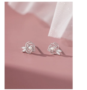 Detail of silver camellia earrings with central pearl and leaf-shaped cubic zirconia