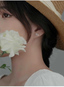 Detail of camellia pearl stud earring with hollow petals and crystals on model