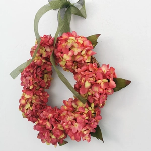 Close-up of red and yellow faux hydrangea wreath with a natural rattan base and ribbon