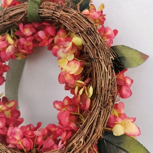 Close-up of pink hydrangea wreath featuring natural vine base and textured green ribbon