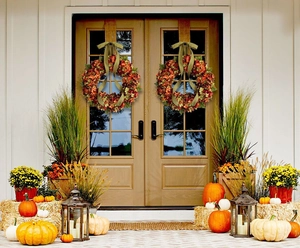 Fall hydrangea wreath with autumn flowers and green ribbons on wooden double doors