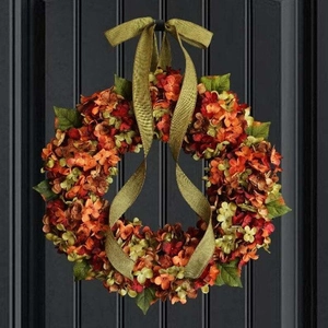 Vibrant fall hydrangea wreath with colorful flowers and green ribbon on black wood door