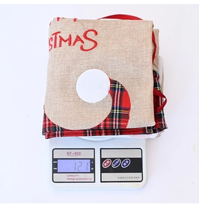 Detailed scale view of a burlap Christmas gift bag with red plaid trim weighing 121 grams