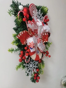 Detail eines Weihnachts-Türhängers mit roten Beeren, Zuckerstangen und Schneeflocken-Schleife