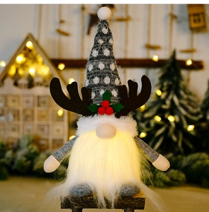 Close-up of glowing LED Christmas gnome with antlers and white beard in cozy home setting