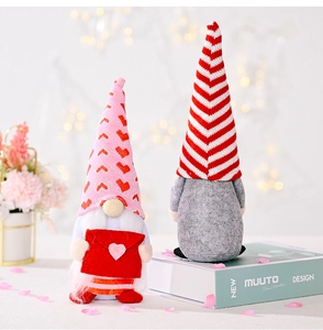Close-up of Valentine gnome plush holding a heart envelope with festive knit details