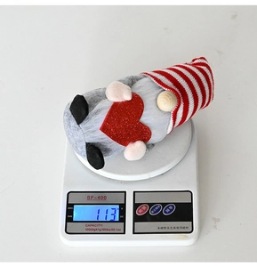 Scales display the 113g weight of a Valentine gnome plush holding a red glitter heart