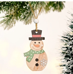 Close-up of wooden snowman ornament with green scarf hanging on a snowy Christmas tree branch