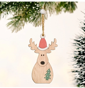 Close-up of wooden reindeer pendant with red Santa hat on a snow-covered Christmas tree
