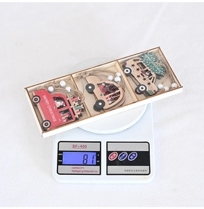 Close-up of three-piece wooden Christmas car ornaments on a digital scale showing weight