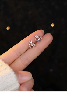 Detail view of silver hollow rose stud earrings with pearls and marquise-cut zircon accents