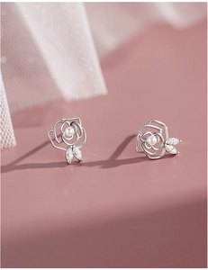 Detail view of silver camellia earrings with central pearl and marquise zircon leaves