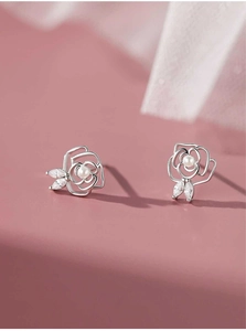 Detailed view of hollow rose earrings with white pearls and marquise zircon leaves