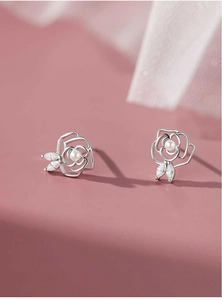 Macro shot of camellia rose earrings with pearl center and marquise zircon leaves
