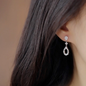Elegant silver teardrop earrings with sparkling zircons worn on model ear