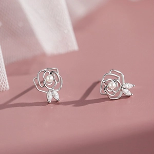 Silver camellia flower earrings with pearl center and marquise zircon leaves on pink background