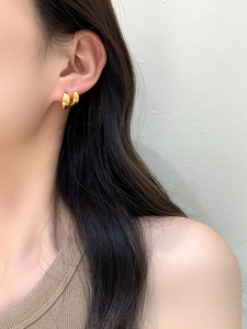 Primo piano di orecchini a cerchio doppi in oro lucido indossati con stile minimalista