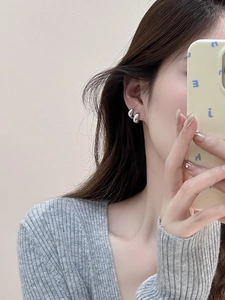 Primo piano di orecchini a perno in argento stile metallo liquido indossati da una modella