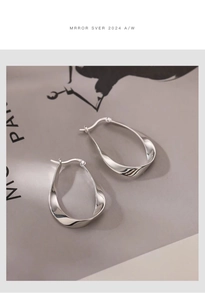 Close-up of S925 sterling silver Mobius twist earrings with hallmark detail on a gray background