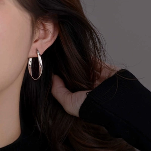 Close-up of elegant silver Mobius twist hoop earrings worn by a model in a minimalist style