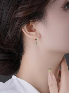 Close-up of geometric cylinder drop earrings with pavé crystal hoops on a female model