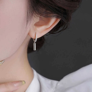 Detail of silver geometric cylinder earrings with sparkling zircon inlay on ear wire
