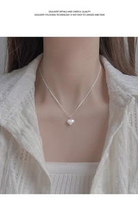 Detailed view of frosted silver heart pendant on a delicate beaded chain necklace